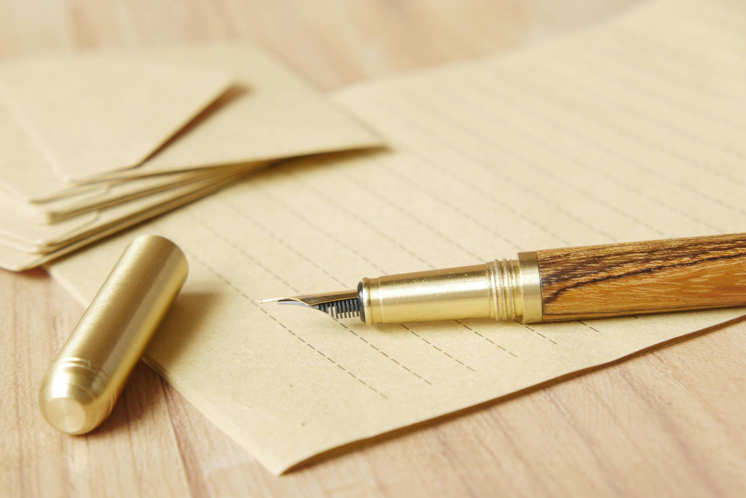 Close-up of a golden fountain pen resting on lined paper, evoking classic correspondence.